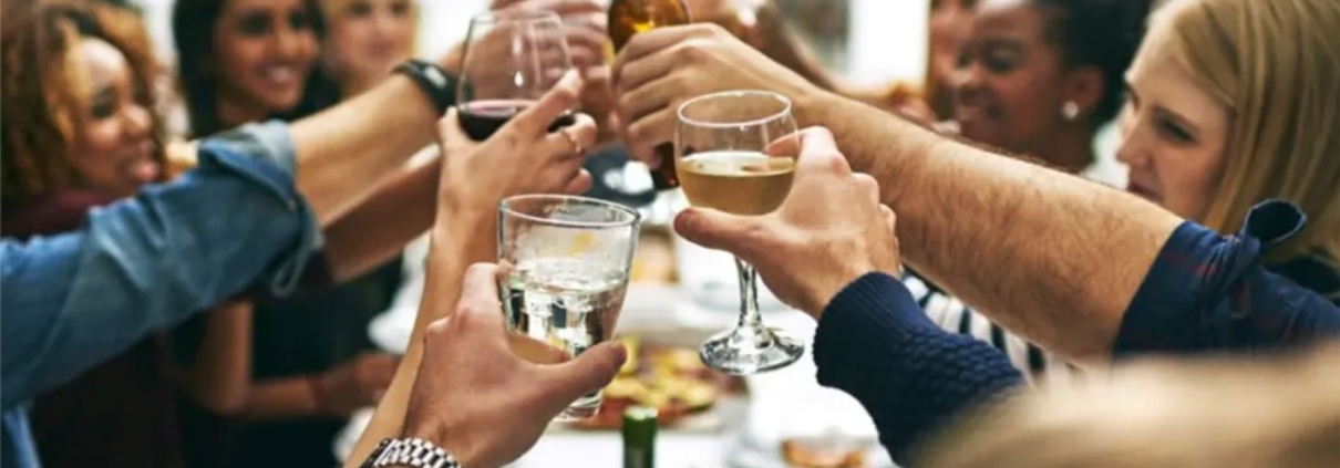 group of friends sitting at the dinner table raising their glasses to cheers