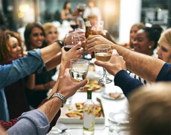 group of friends sitting at the dinner table raising their glasses to cheers